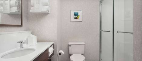 A modern bathroom with a white sink, toilet, and glass shower enclosure.