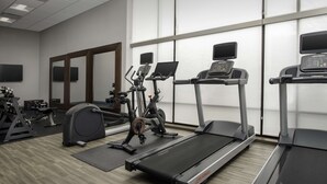 Un gimnasio con cintas de correr, elípticas y equipos de pesas.