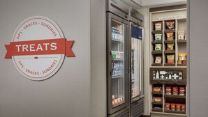 Mostrador refrigerado con aperitivos y bebidas, y un cartel que indica una sección de golosinas.