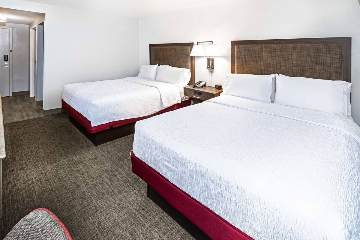 Een hotelkamer met twee bedden, een bureau en een stoel.
