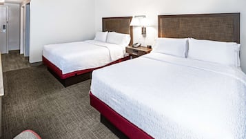 Een hotelkamer met twee bedden, een bureau en een stoel.