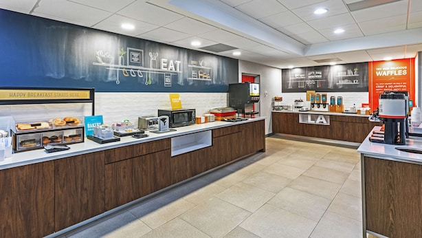 Un área de desayuno moderna con una barra que exhibe pastelería y una máquina de café.