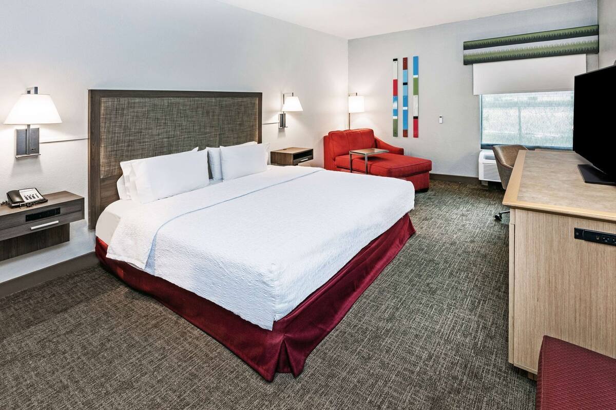Een hotelkamer met een groot bed, een bureau, een stoel en een televisie.