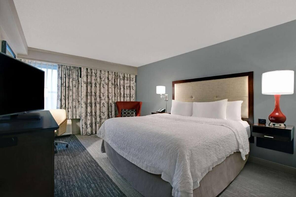 Une chambre d’hôtel avec un grand lit, une télévision, un bureau avec une lampe et une chaise.