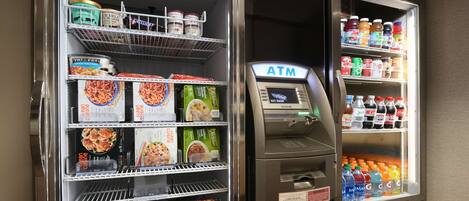 A vending machine with a variety of food items and a separate ATM.