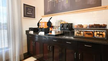 A kitchen with dark wooden cabinets, a coffee machine, a toaster, and a display case with bread.