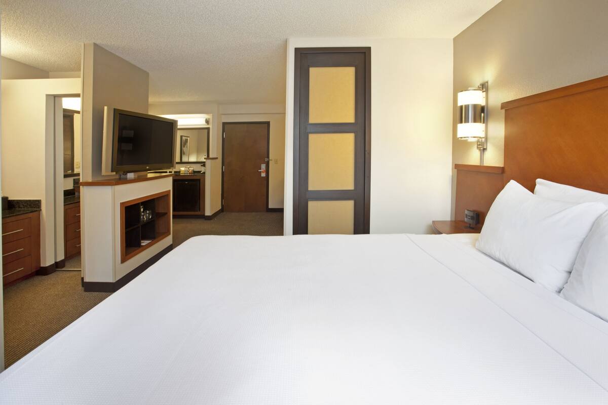 Una habitación de hotel con una cama grande, televisión, escritorio y puerta que da a un baño.
