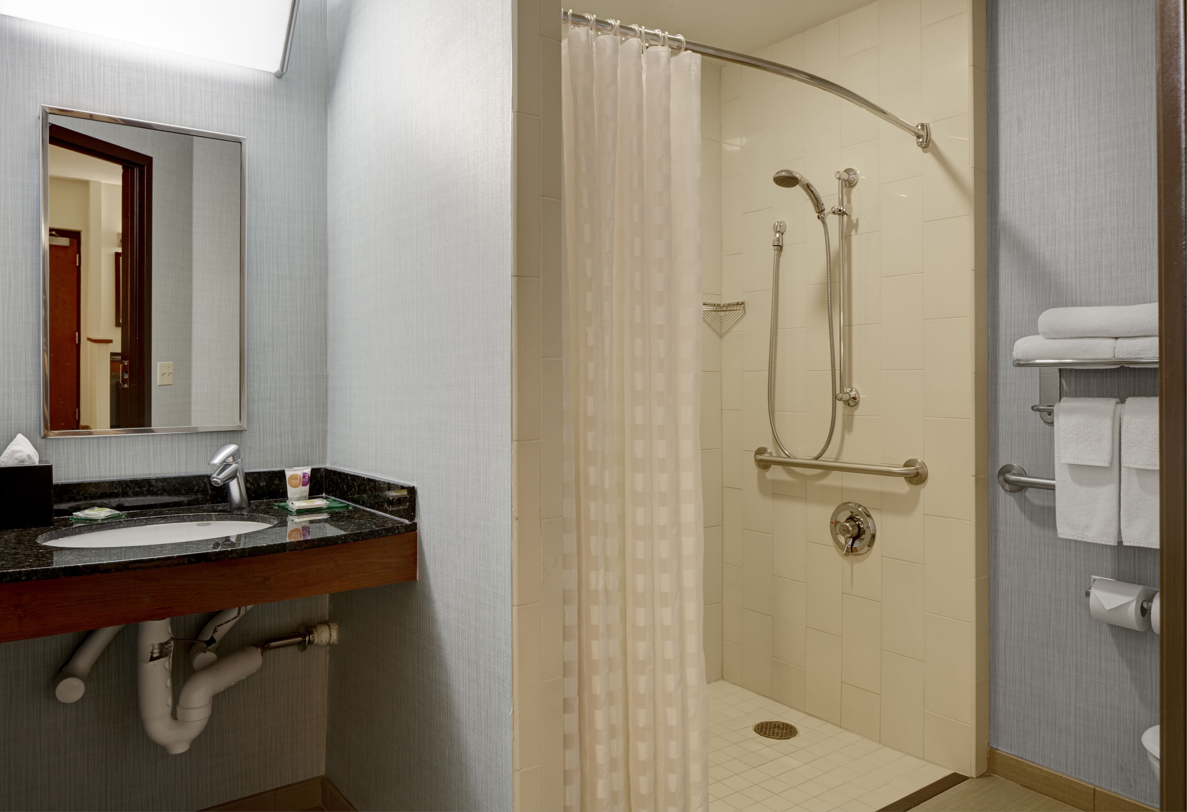 Une salle de bain équipée d’un lavabo, d’un miroir, d’une douche et d’un porte-serviettes.
