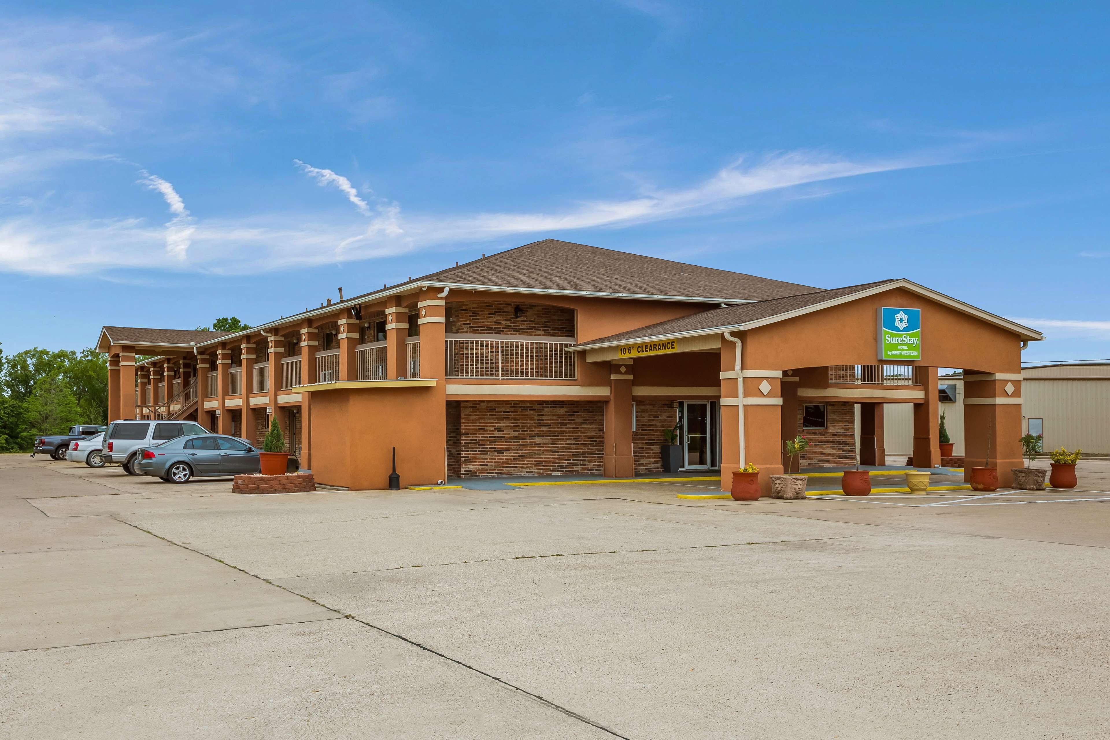 Un hotel con fachada de ladrillo, acceso cubierto y aparcamiento.