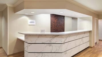 A reception desk with a marble design, a sign indicating 'Marriott Bonvoy', and a patterned wall behind it.