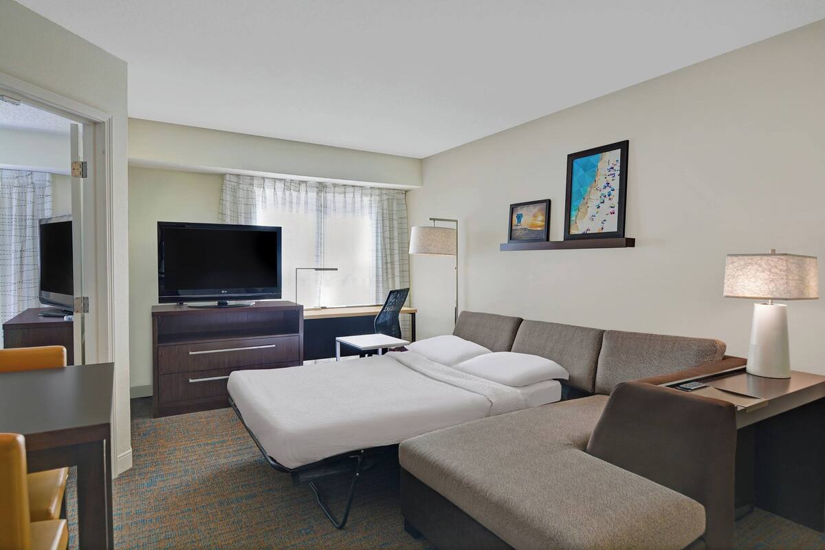 A hotel room with a bed, a desk, a television, and a lamp.