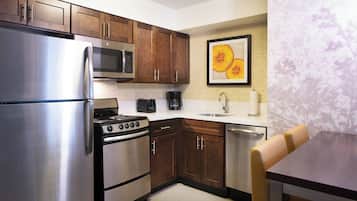 Una cocina moderna con electrodomésticos de acero inoxidable, armarios de madera y un comedor con mesa y sillas.