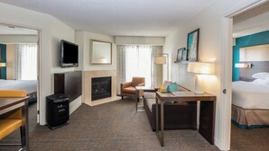Ein Hotelzimmer mit Bett, Schreibtisch, Stuhl, Fernseher, Kamin und Teppichboden.
