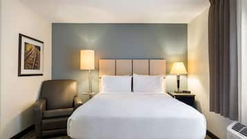 A hotel room with a large bed, two bedside lamps, a chair, a framed picture on the wall, and a window with curtains.