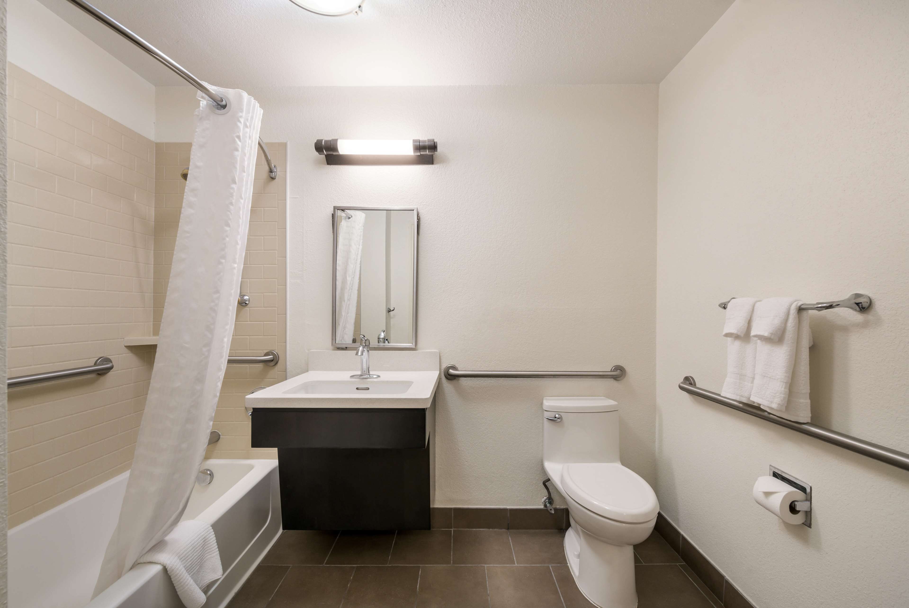 Et moderne badeværelse med badekar, vask, toilet og gelændere.