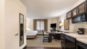 A hotel room with a bed, a desk, a chair, a television, a microwave, and a coffee maker. - Sonesta Simply Suites Hampton (Hampton)