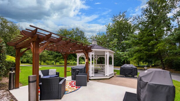 An outdoor patio with a gazebo, seating area, and grill. - Sonesta Simply Suites Hampton (Hampton)