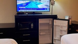 A hotel room with a television displaying a news channel, a refrigerator, and a bed. - Hualapai Lodge (Peach Springs)