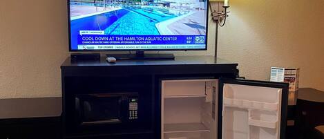 Une chambre d’hôtel équipée d’une télévision diffusant une chaîne d’information, d’un réfrigérateur et d’un lit.