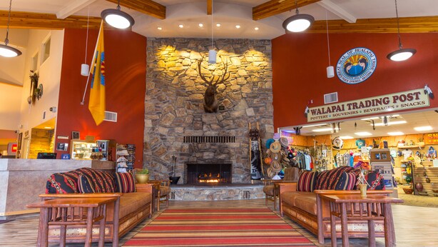 A lobby with a stone fireplace, wooden furniture, and a sign for 'Walapai Trading Post'. - Hualapai Lodge (Peach Springs)