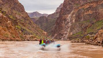 Un grupo de personas haciendo rafting en un cañón con paredes rocosas escarpadas y un río.