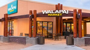The exterior of a Walapai Market with a wooden pergola entrance, outdoor seating, and a clear sky. - Hualapai Lodge (Peach Springs)