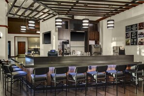 A bar area with a long counter and multiple bar stools. - Hyatt Place Cincinnati Airport / Florence (Florence)