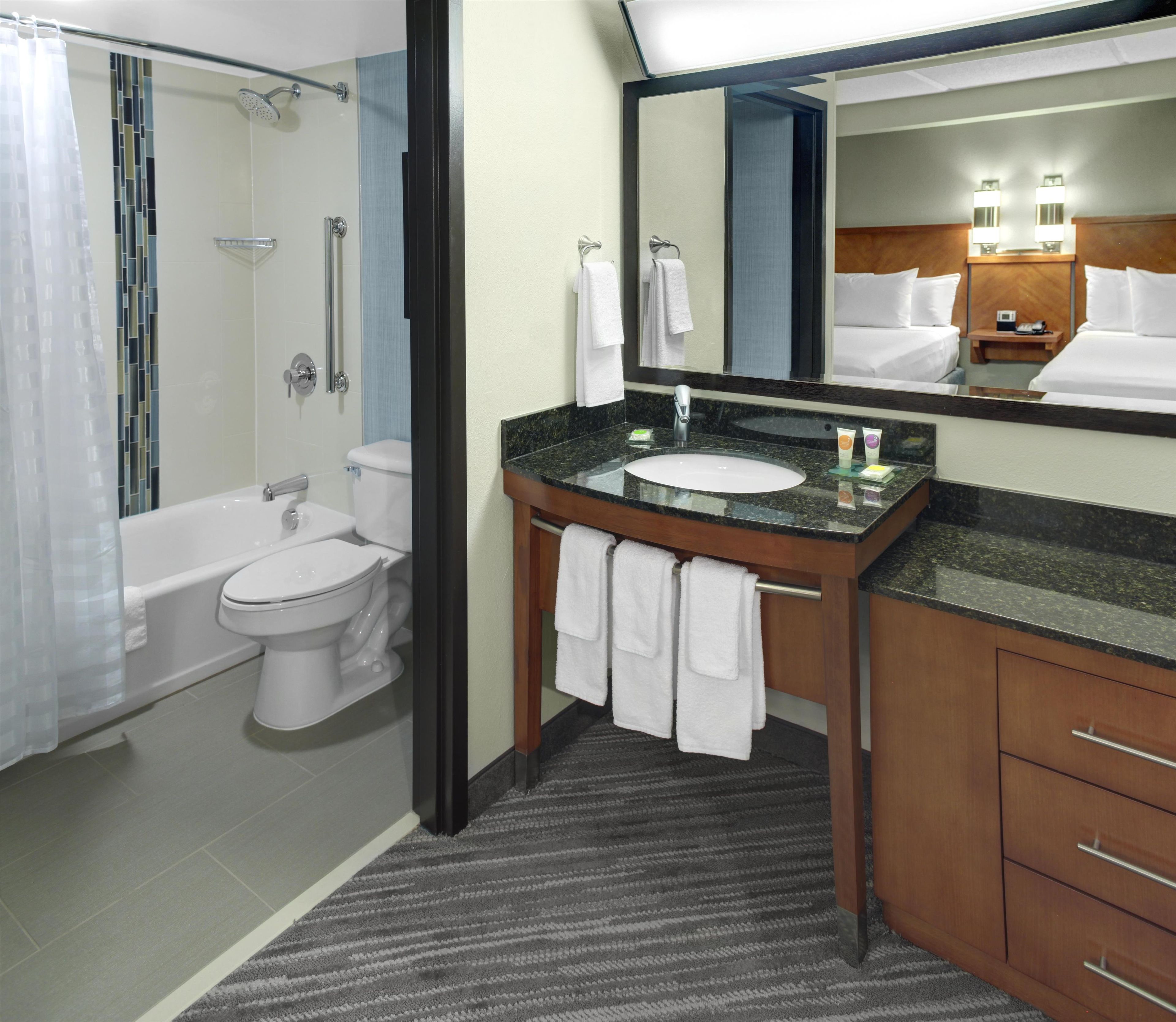 A hotel bathroom with a bathtub, toilet, sink, and a large mirror.