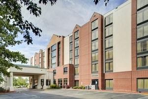 A multi-story hotel with a brick facade, large windows, and a covered entrance.