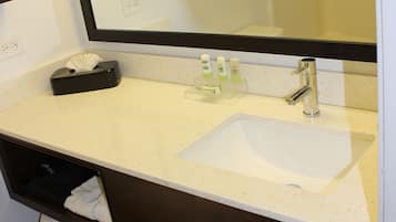 Une salle de bain avec un lavabo blanc, un miroir, des œuvres d’art encadrées et un porte-serviettes.
