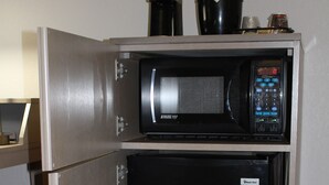 A compact kitchenette with a microwave and a small refrigerator.