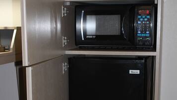 Una kitchenette compacta con microondas y un refrigerador pequeño.