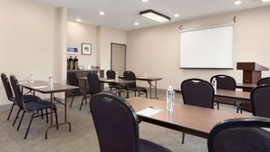 A conference room with multiple tables and chairs, a projector screen, and a coffee station.