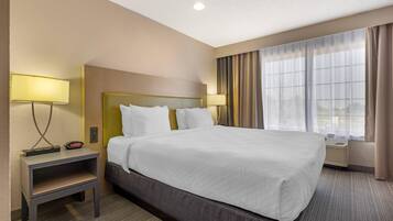 A hotel room with a large bed, bedside lamps, a nightstand, and a window with curtains.