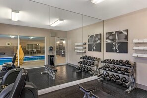 A gym with exercise equipment, a mirror, and a pool area visible through the glass doors. - Country Inn & Suites by Radisson Romeoville I-55 (Romeoville)