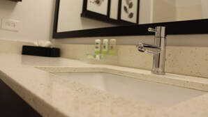 A bathroom with a modern sink, a mirror, and framed artwork on the wall.