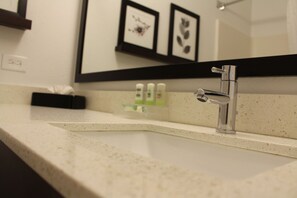 A bathroom with a modern sink, a mirror, and framed artwork on the wall.