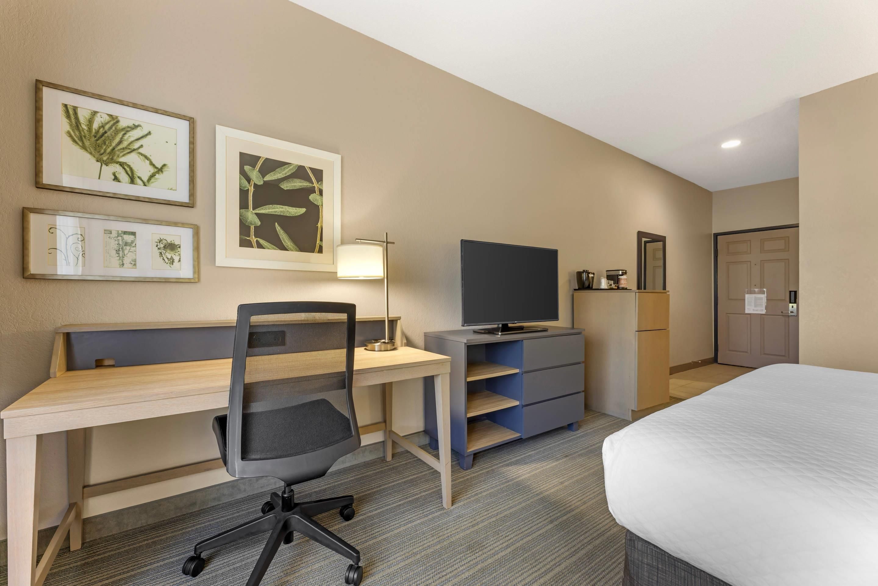 Une chambre d’hôtel équipée d’un bureau, d’une chaise, d’une télévision, d’une armoire et d’un lit.
