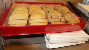 A display case with cookies and a stack of papers.