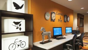A workspace with two computer monitors, a keyboard, and office chairs. There are shelves with illuminated artwork, including a butterfly, a bird, and a bicycle. - Fairfield Inn by Marriott Greenville-Spartanburg Airport (Greenville)