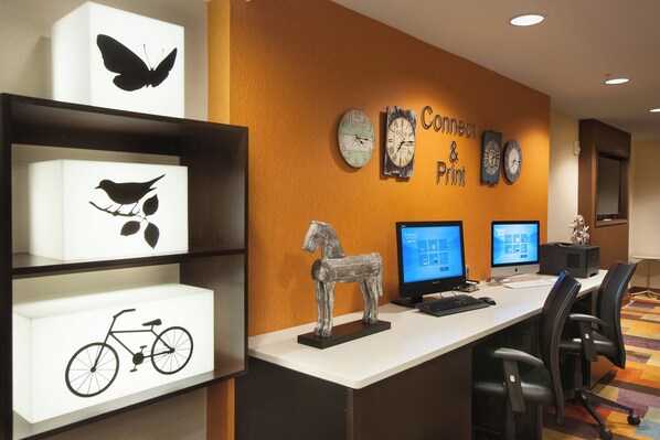 A workspace with two computer monitors, a keyboard, and office chairs. There are shelves with illuminated artwork, including a butterfly, a bird, and a bicycle.