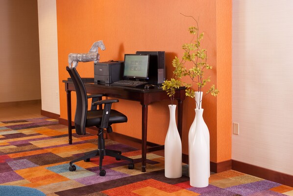 A workspace with a desk, chair, computer, and two white vases with plants.
