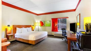 A hotel room with a bed, desk, chair, and a window with a view.