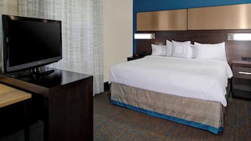 A hotel room with a bed, a TV on a desk, and a nightstand.
