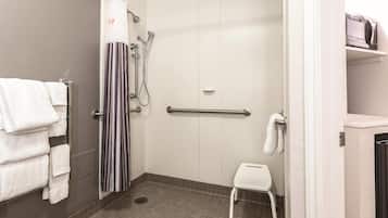 A shower area with a grab bar, a white towel rack, a striped shower curtain, and a white step stool.