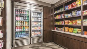 A snack and beverage area with two refrigerators stocked with drinks and snacks, and shelves with various packaged snacks. - La Quinta Inn & Suites by Wyndham Atlanta Alpharetta (Alpharetta)