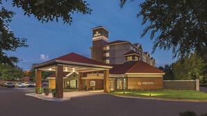 A hotel with a prominent tower, a covered entrance, and a well-maintained lawn. - La Quinta Inn & Suites by Wyndham Atlanta Alpharetta (Alpharetta)