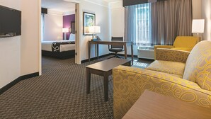 A hotel room with a bed, a desk, a chair, a sofa, and a TV. - La Quinta Inn & Suites by Wyndham Atlanta Alpharetta (Alpharetta)
