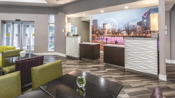 A hotel lobby with a reception desk, seating area, and a large window overlooking a cityscape. - La Quinta Inn & Suites by Wyndham Atlanta Alpharetta (Alpharetta)