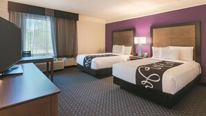 A hotel room with two beds, a desk, a chair, a TV, and a window with curtains. - La Quinta Inn & Suites by Wyndham Atlanta Alpharetta (Alpharetta)